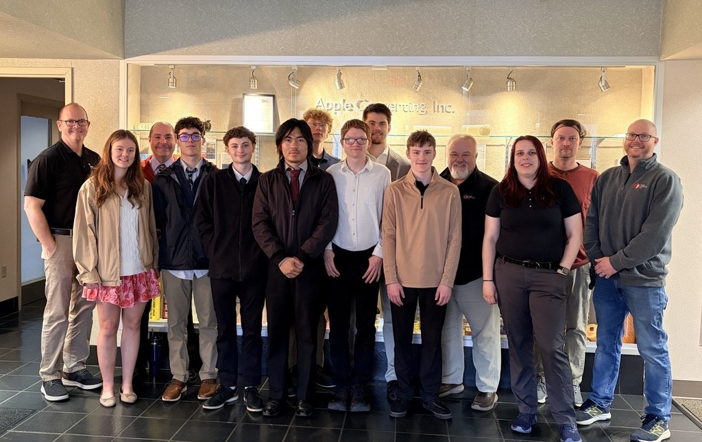 7 students, the Engineering instructor, and 6 staff members from Apple Converting standing in front of the company sign.