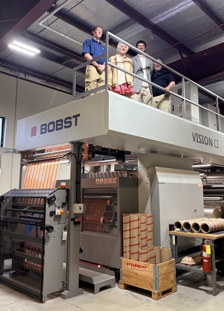 1 students and 3 staff members standing on a machine