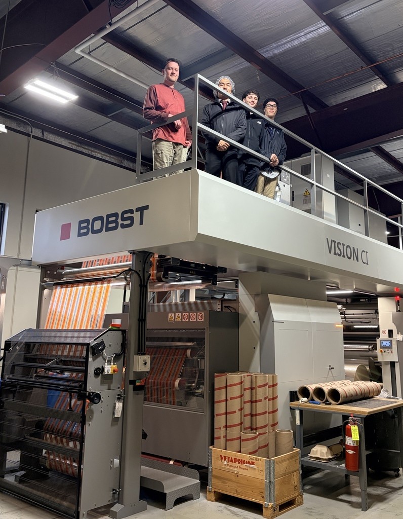 4 students standing on a machine