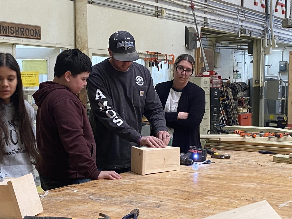 Building Trades instructor working on birdhouse while student and another staff member watch