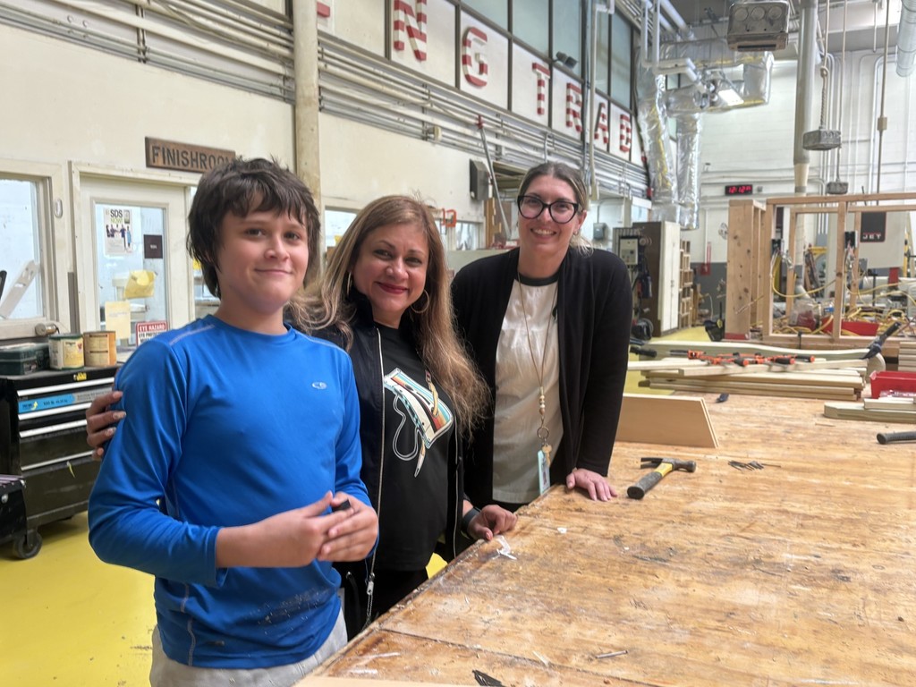 Student and two staff members standing by a woodwork bench