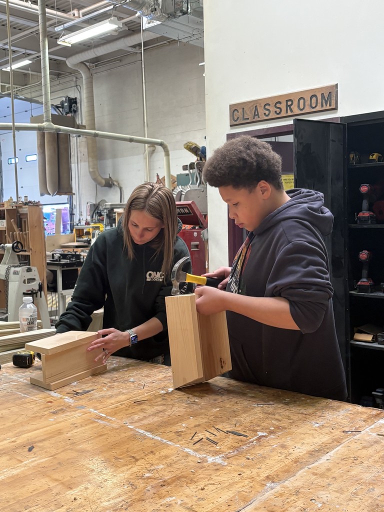 Student and staff member working on birdhouses with hammers