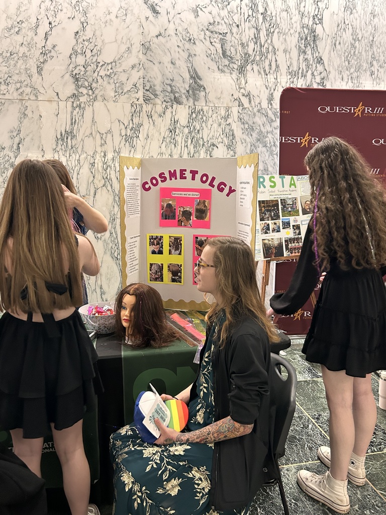 Cosmetology students around a presentation board and a mannequin head on display