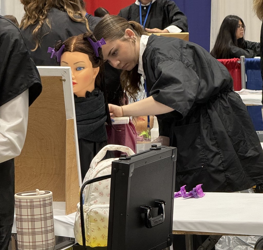Student at a hair cutting station performing a cut on a mannequin head