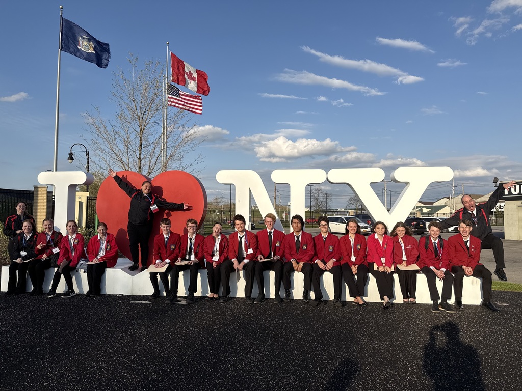15 students and 3 chaperones sitting and standing on the I heart NY sign