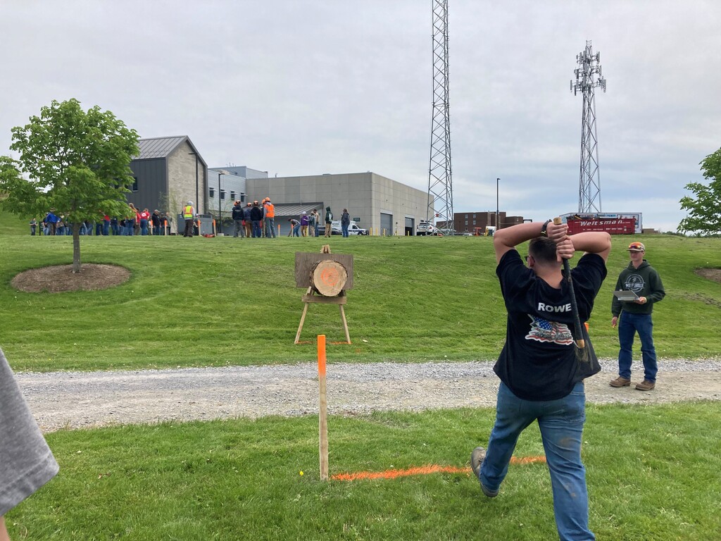 Student throwing an ax at a target with a score person standing to the side.