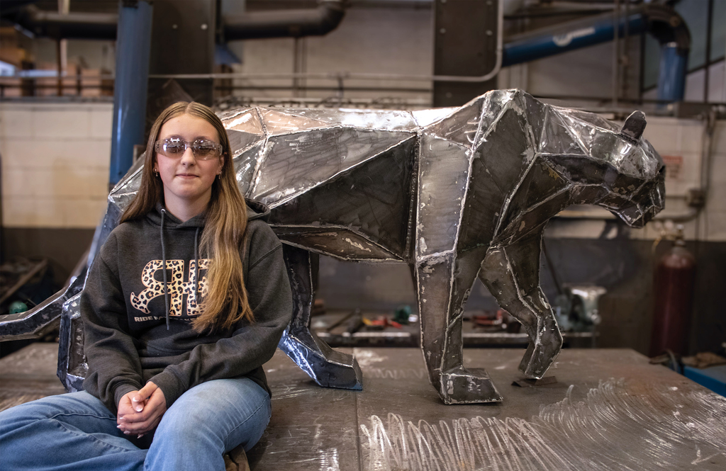 Student sitting in front of the welded panther they created.