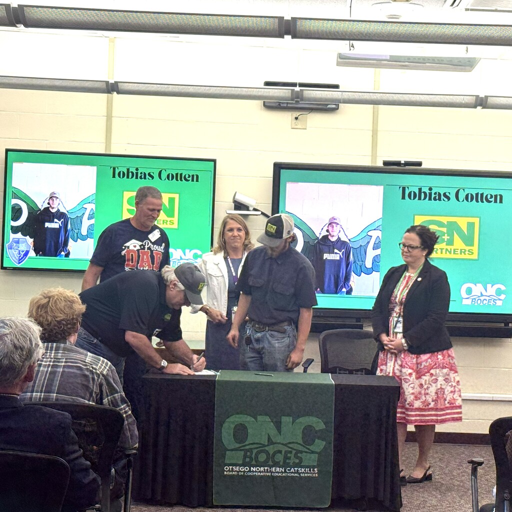 Business representative is signing the commitment letter while the student, parent, school superintendent, and ONC BOCES district superintendent look on.