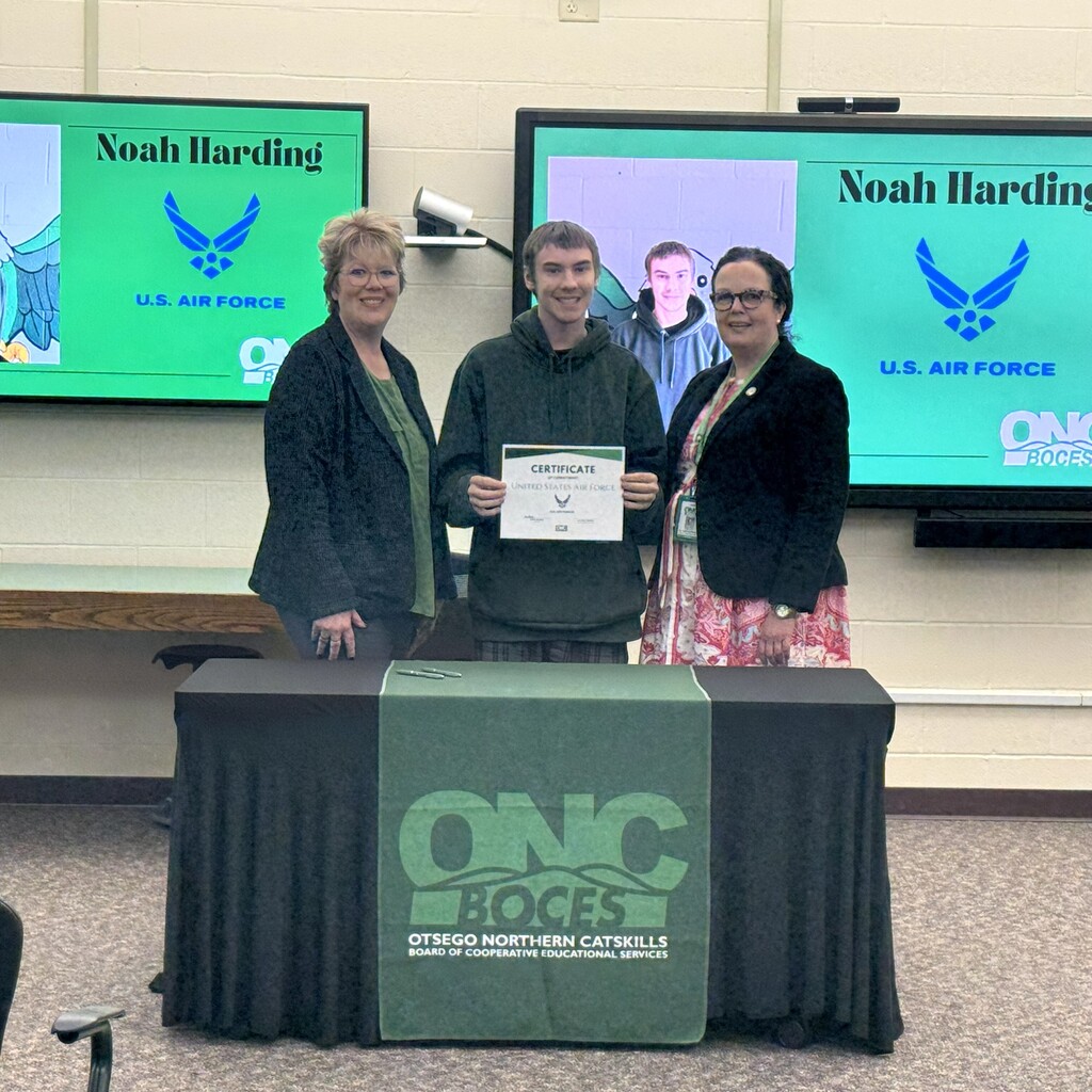 Director of student programs, student holding a certificate, and ONC BOCES district superintendent posing behind a table with a black tablecloth and a green ONC BOCES banner.