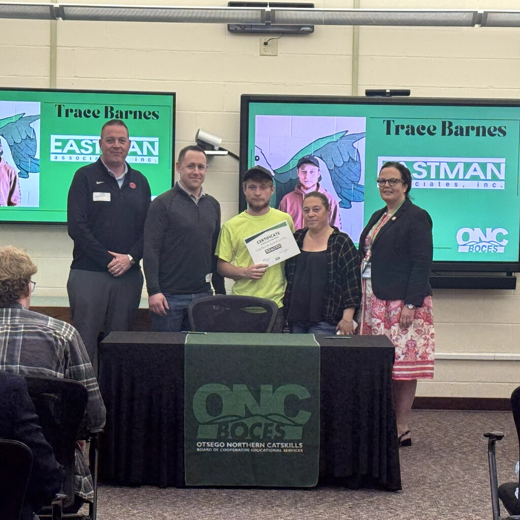 Student holding a certificate stands with parents and business representative and ONC BOCES district superintendent.