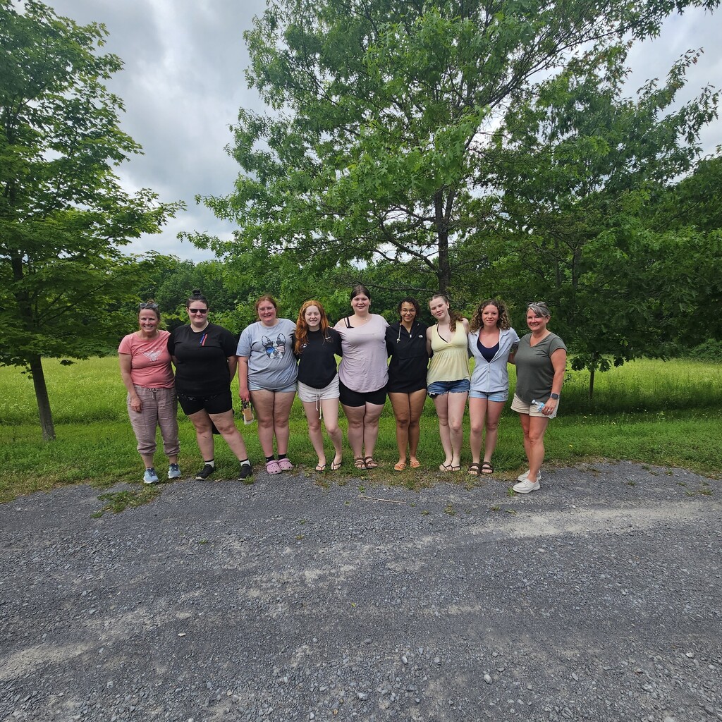 7 students, instructor, and licensed teaching assistant standing in a line posing at the park.