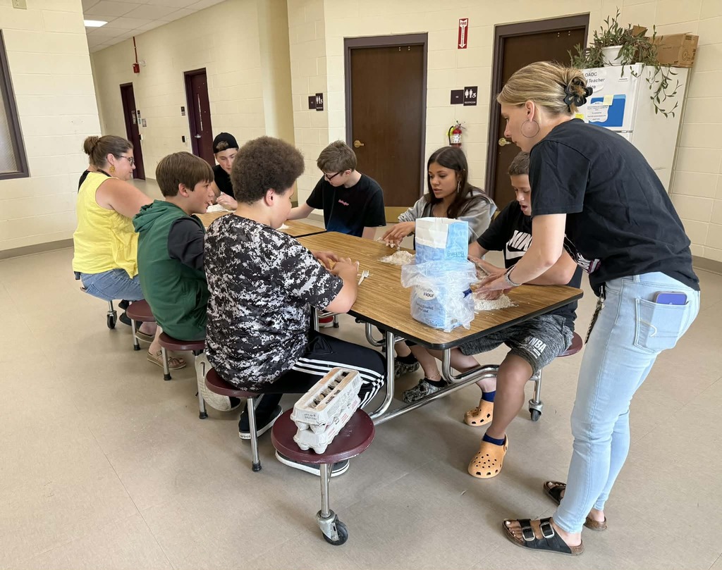 5 students and 3 staff members working at a table with pasta dough
