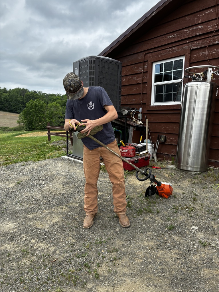 Student working on a weed eater outside