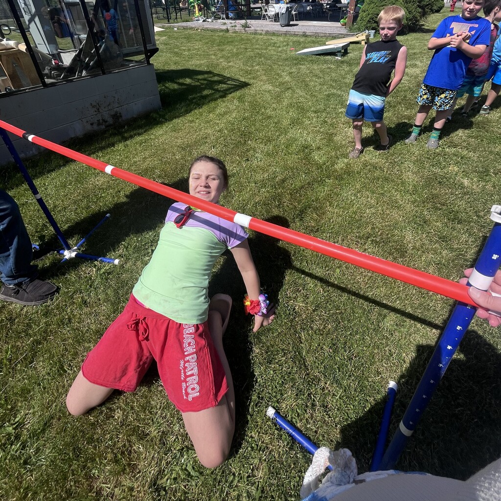 Student going under a limbo stick while other students watch