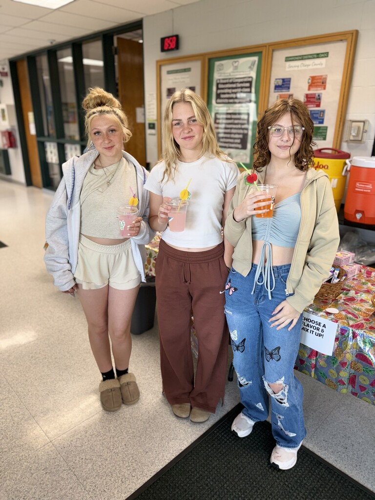 3 high schoolers standing near a table with drinks and straws