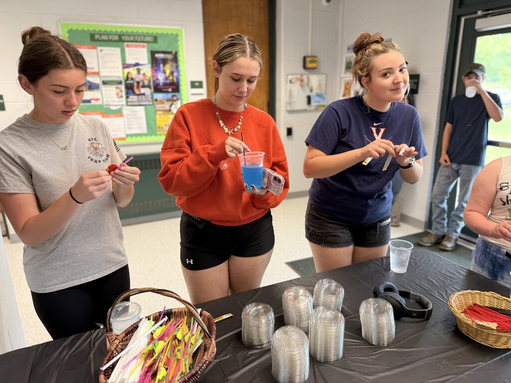 Three high school students at the table deciding on the flavor packets to put in their cups of water