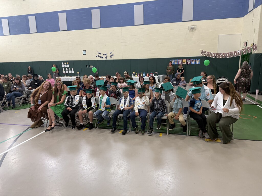 Photo of large group of students, staff, and guests in the gym sitting in chairs