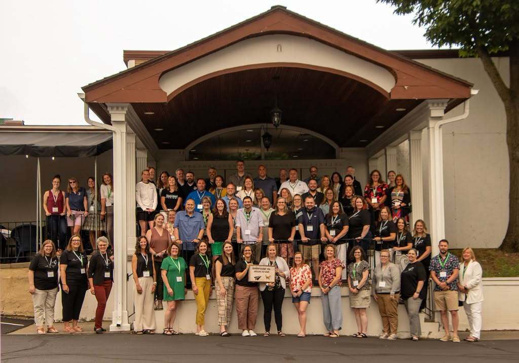 The large group of participants gathered for a picture outside in front of a building
