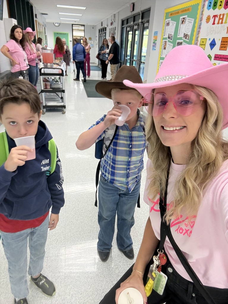 Sraff member with ppink hat and sunglasses taking a selfie with two young students drinking lemonade