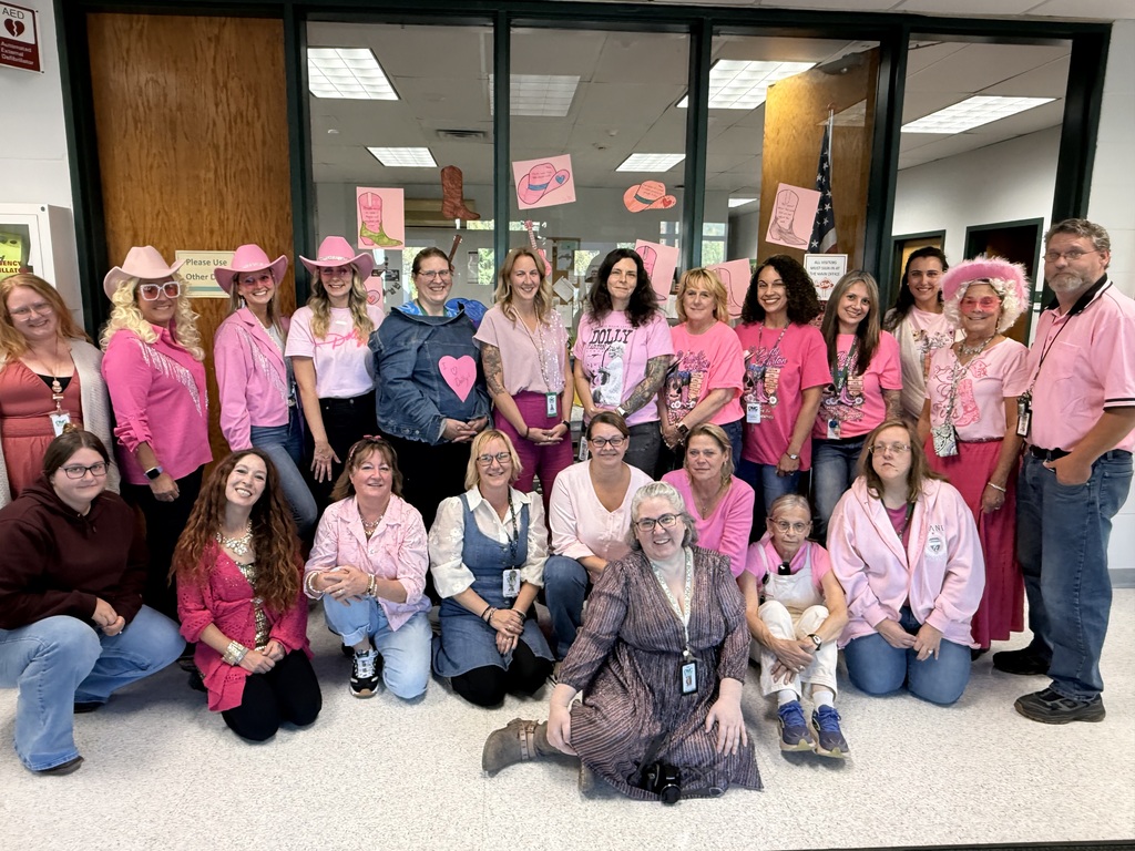 22 staff members posing for a picture wearing their Dolly Parton attire