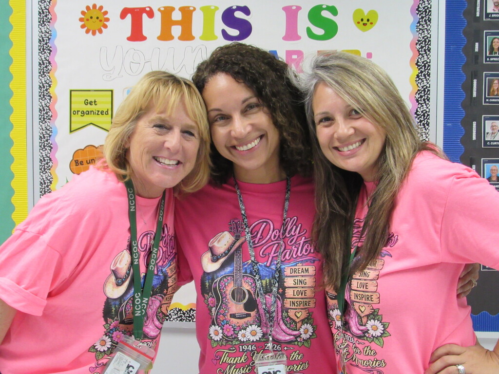 Three staff members wearing pink Dolly Parton shirts