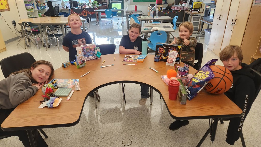 5 students sitting at one table with their auction winnings