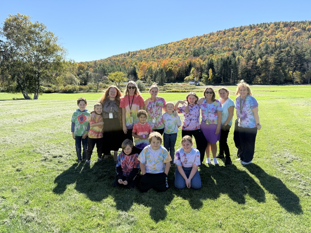 9 students and 6 staff members posing outside for a picture in their tie dyed shirts