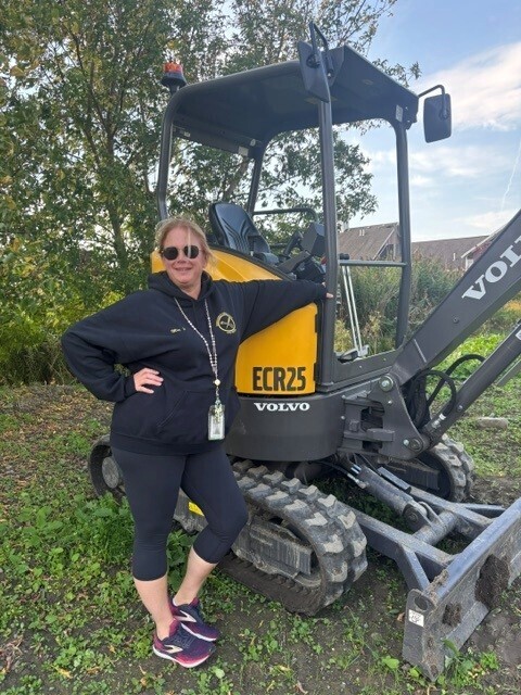 Cosmetology teacher standing with a piece of outdoor machinery
