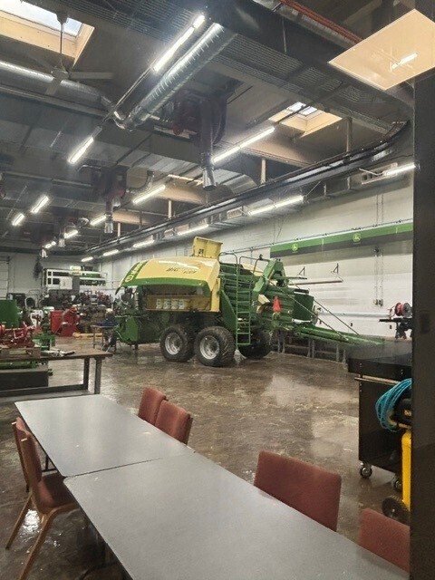 Inside a large building showing a large green and yellow piece of equipment