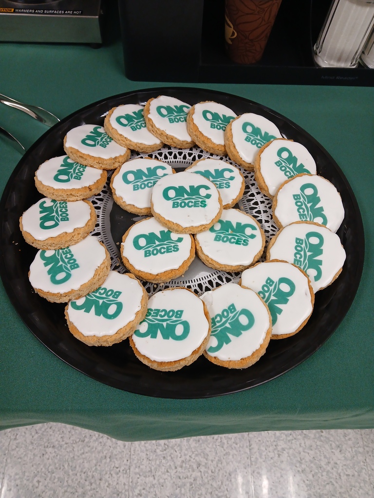 A tray of brown cookies with white frosting and the ONC BOCES green logo on the white frosting.