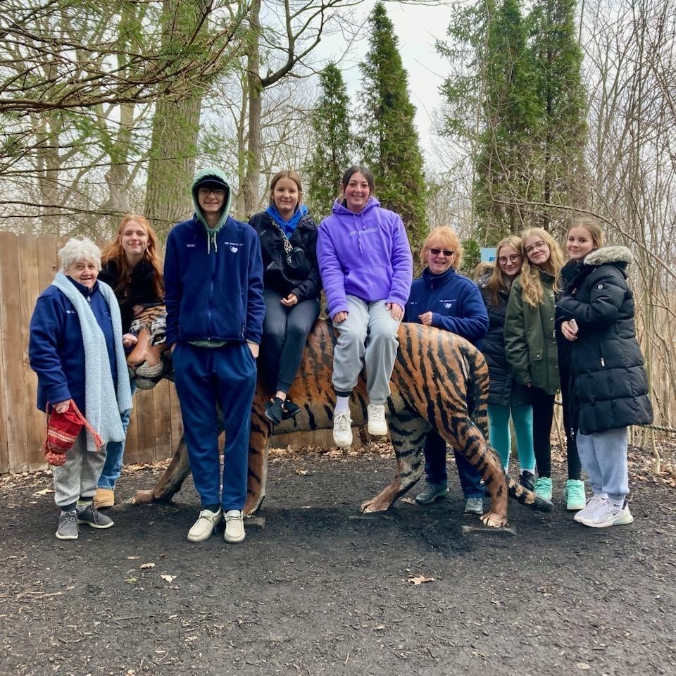 2 staff and 7 students posing with tiger statue.