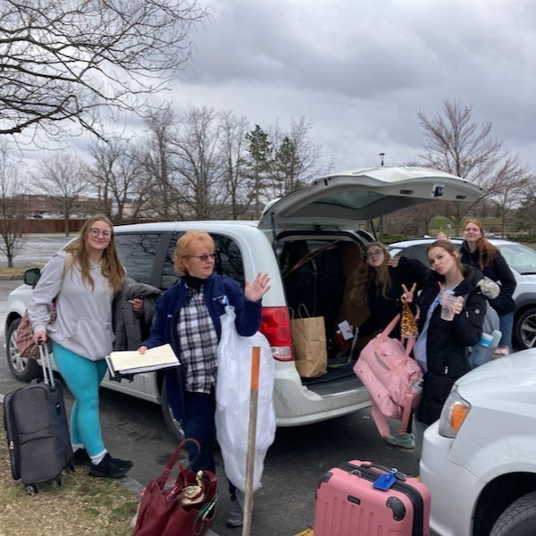 Students and teacher unpacking van in parking lot.