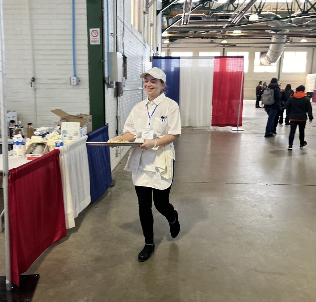 Student smiling with pan of baked goods