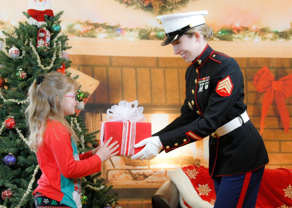 Toys for Tots image of a Marine handing a girl a gift