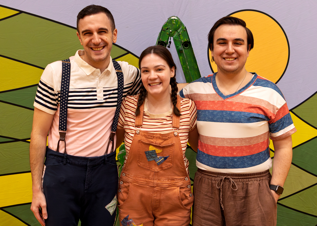 The cast poses in front of their backdrop