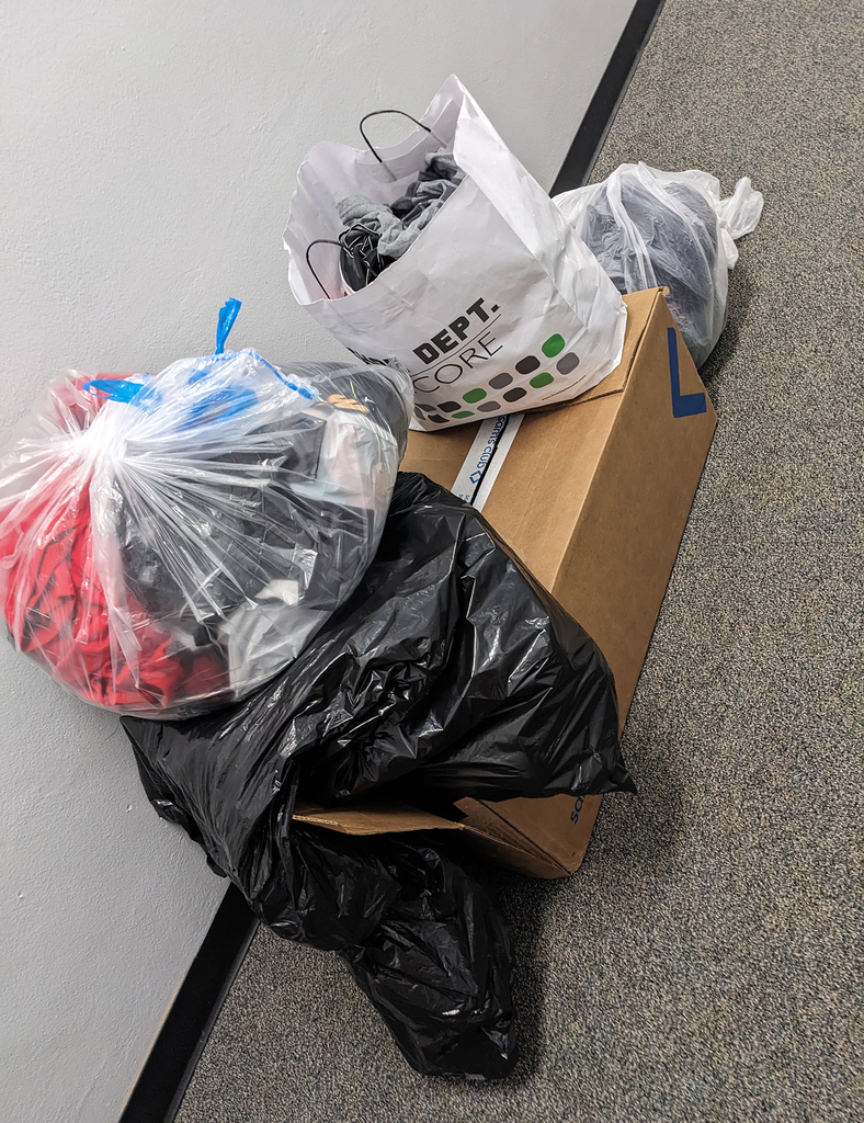 Wagon and bags filled with donated clothing and items for Karter’s Closet in a school hallway.