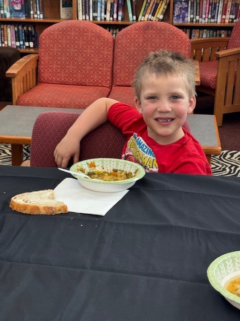 A smiling student with his soup bowl