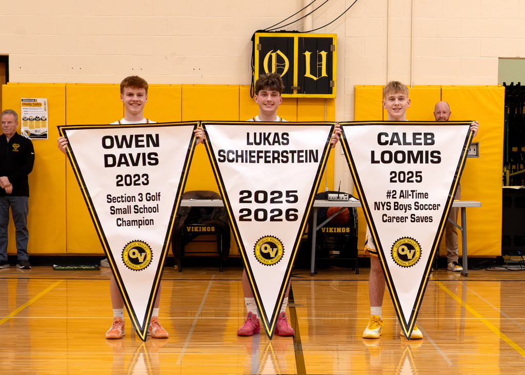 Three seniors with their banners celebrating their individual accomplishments