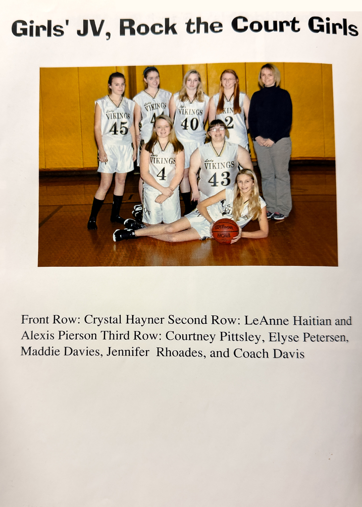 2012 Otselic Valley JV Girls Basketball team posed for a yearbook photo in the gym, wearing white Vikings uniforms, with players standing and kneeling around a basketball.