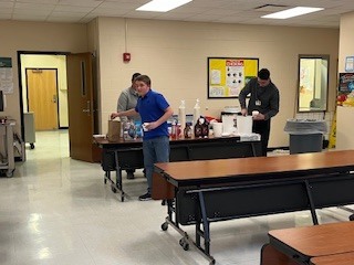 Staff preparing ice cream and toppings on a serving table in the school cafeteria.