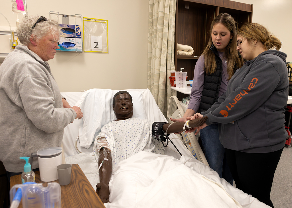 Students try to find a pulse on a medical manikin