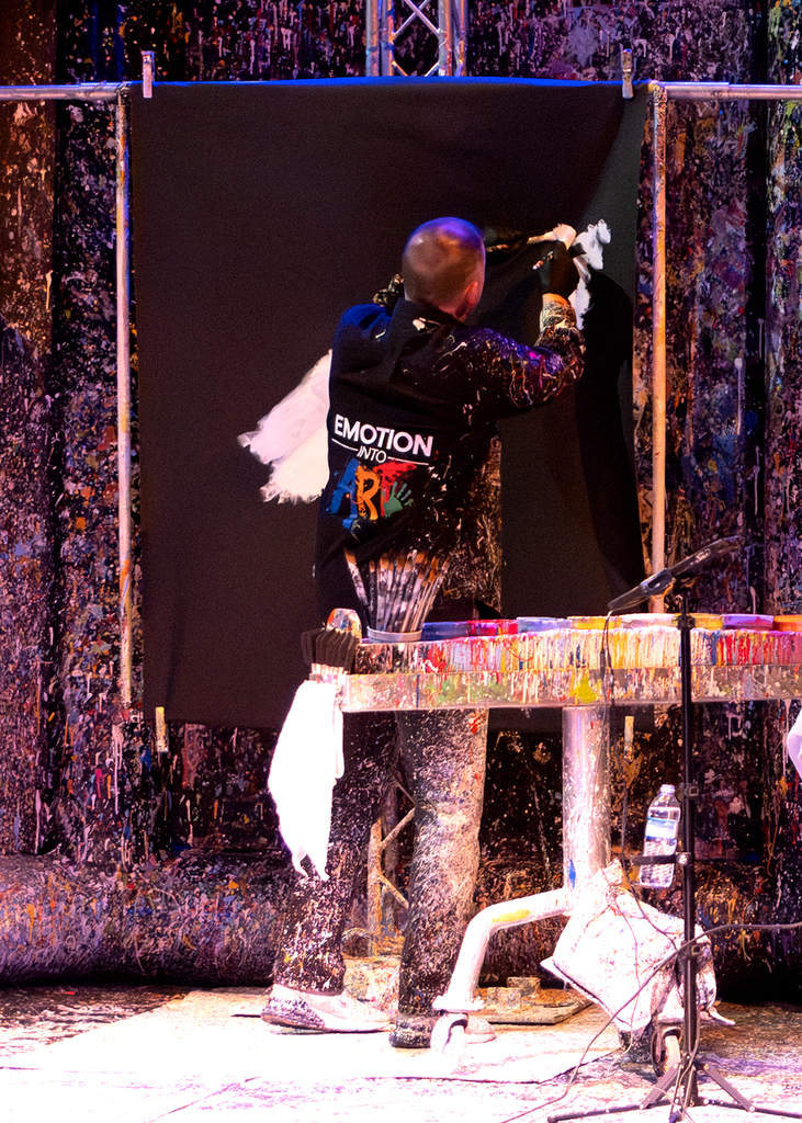Tom working on a painting on stage