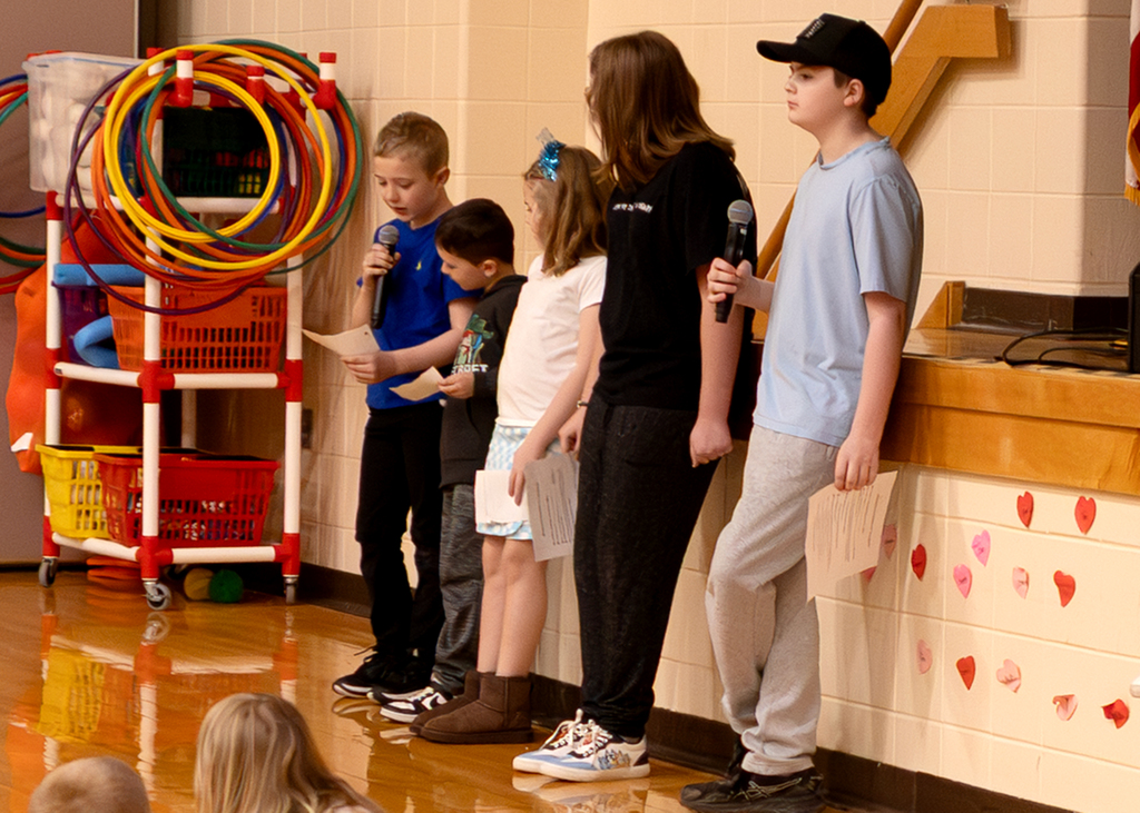 Several students stand near the stage