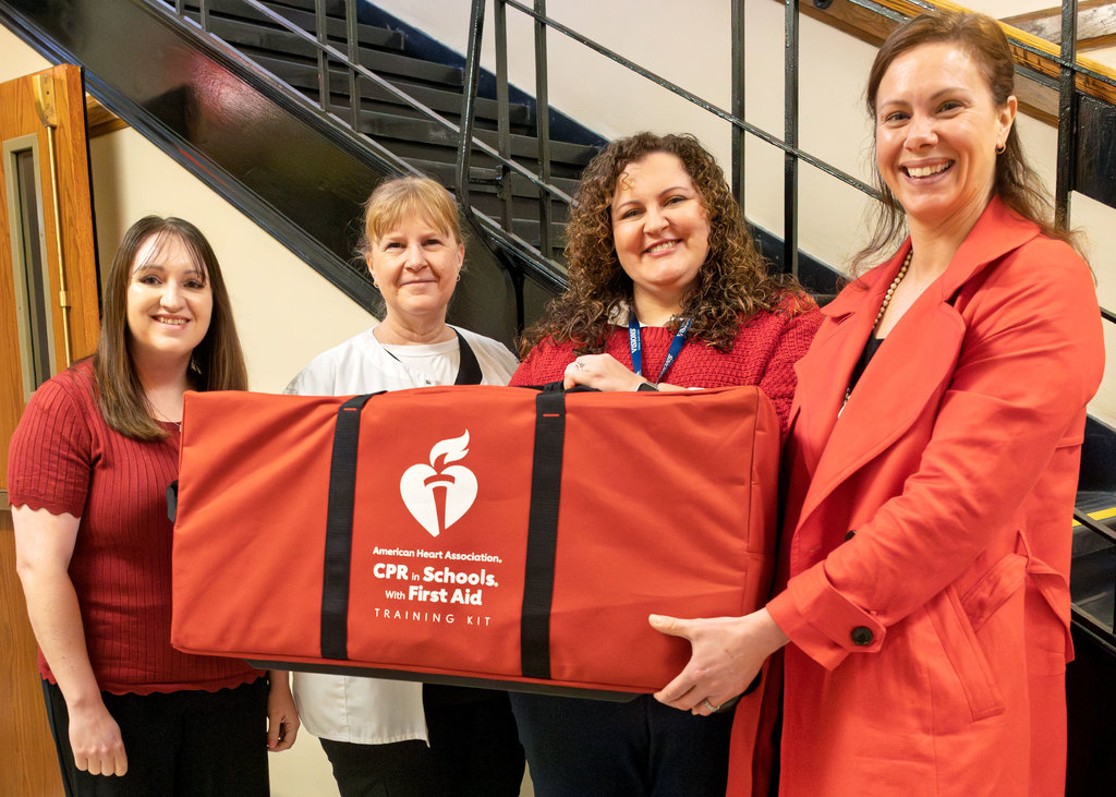 Representatives from the American Heart Association and Visions Federal Credit Union present a CPR in Schools training kit to Otselic Valley School Nurse Stacie Morse.