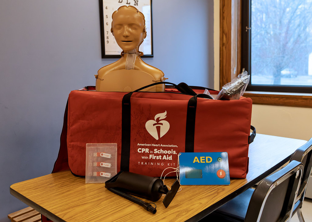 American Heart Association CPR in Schools training kit displayed on a table at Otselic Valley, including an inflatable CPR training mannequin, AED training device, pump, and instructional materials.