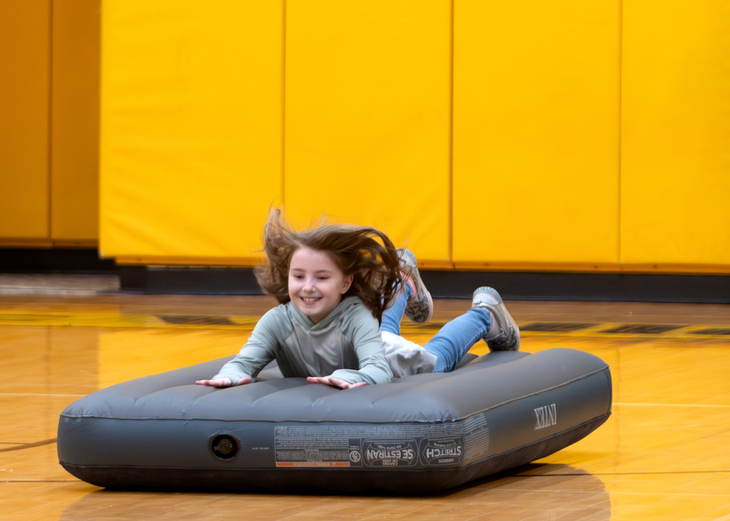 A student slides on an inflatable mattress