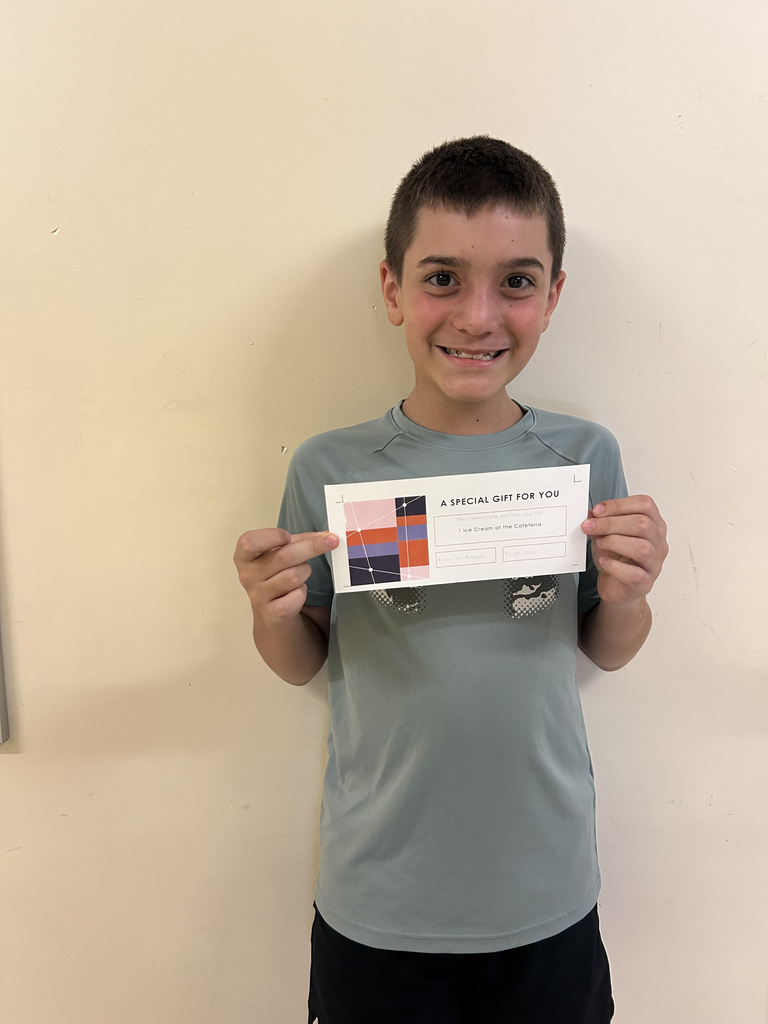 One Otselic Valley student stands indoors against a light-colored wall, smiling while holding a certificate for the Ice Cream March Madness Bracket Challenge.