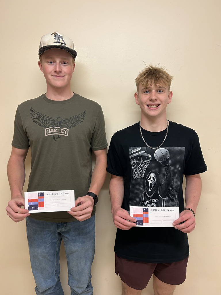 Two Otselic Valley students stand indoors against a light-colored wall, smiling while holding certificates for the Ice Cream March Madness Bracket Challenge.