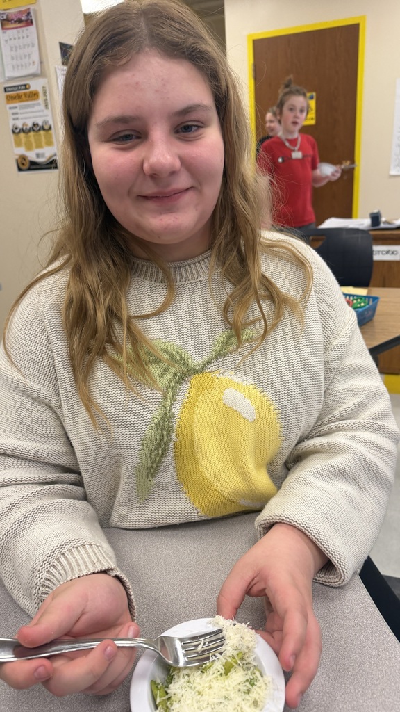 Student smiles while holding bowl of ramp pesto pasta.