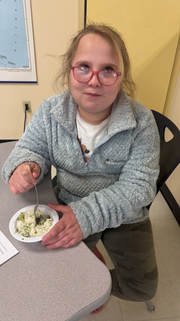 Student enjoys bowl of ramp pesto pasta at table.